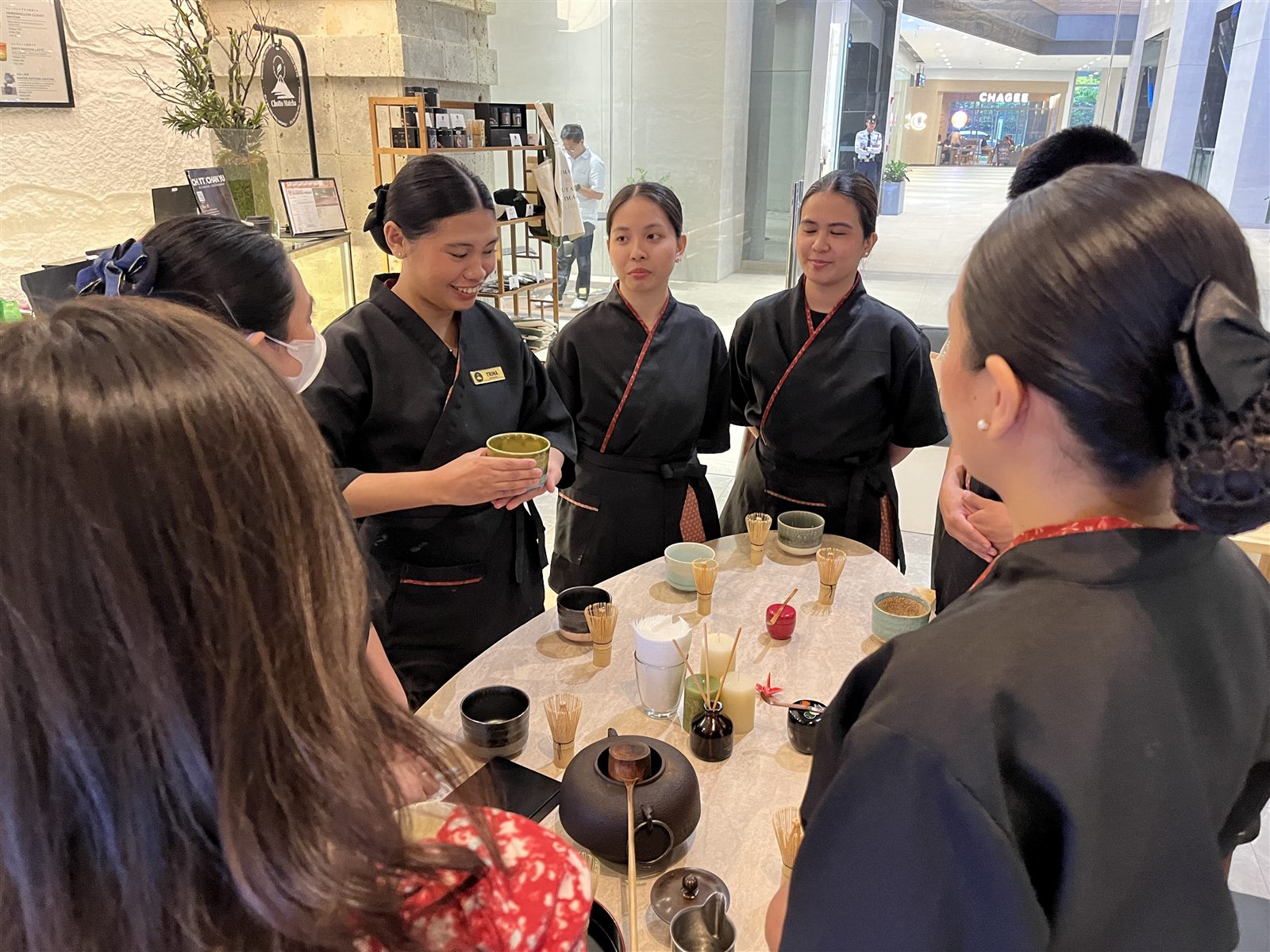 Staff gathered around properly arranged tea utensils during training
